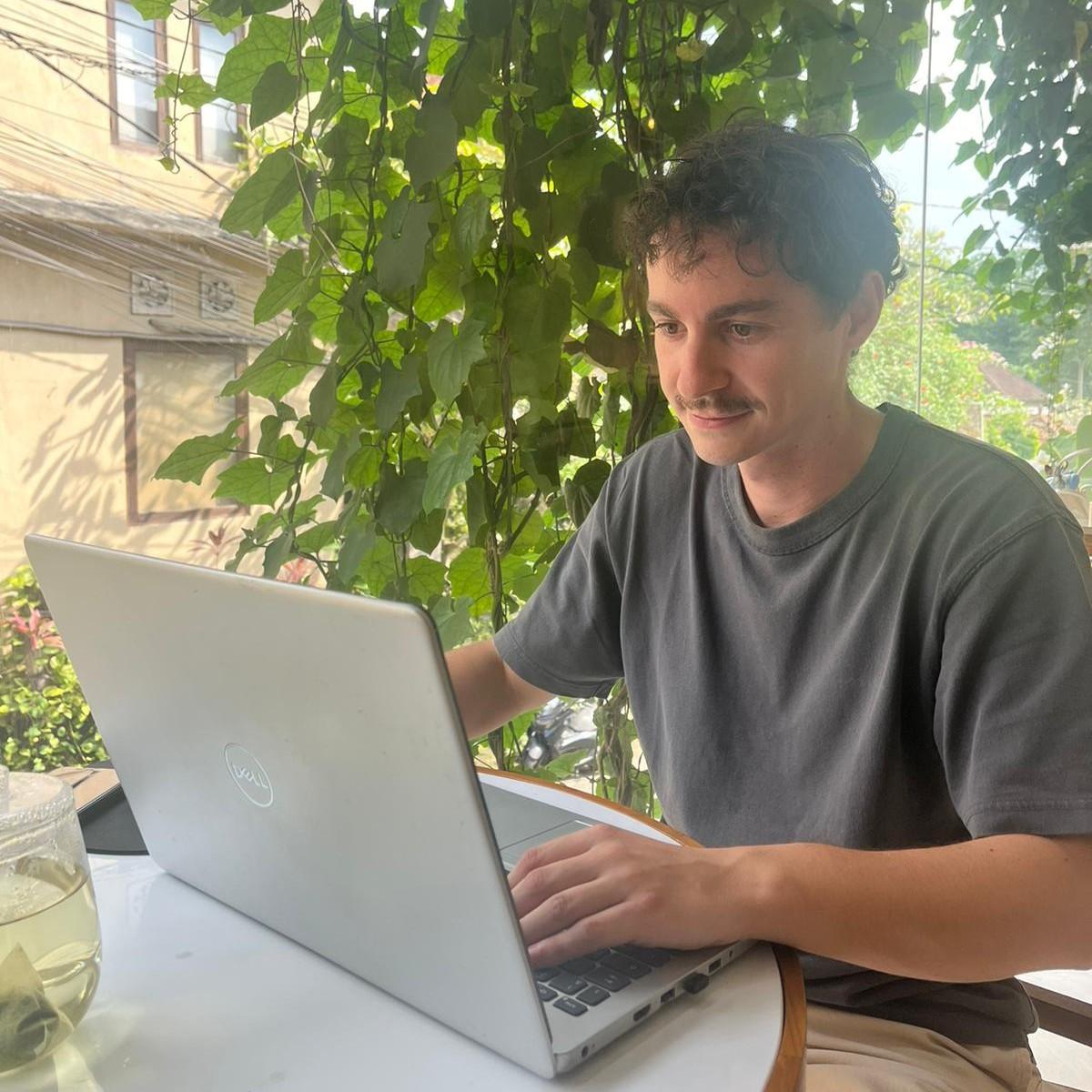 Mathieu Quentel, consultant SEO, travaillant sur son ordinateur portable dans un café lumineux entouré de verdure